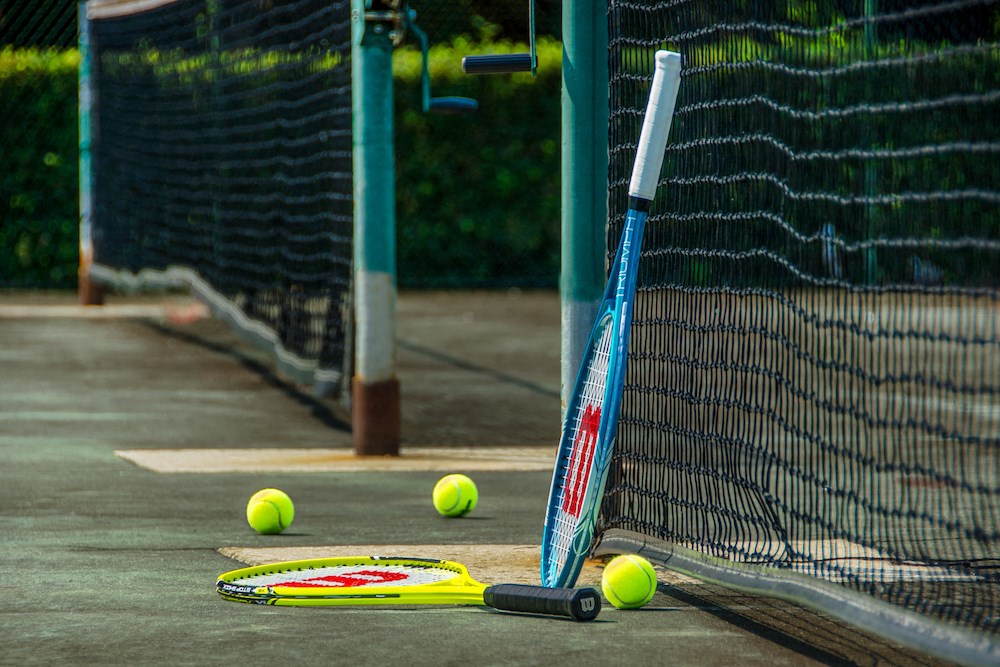 a tennis racket and tennis balls next to a net