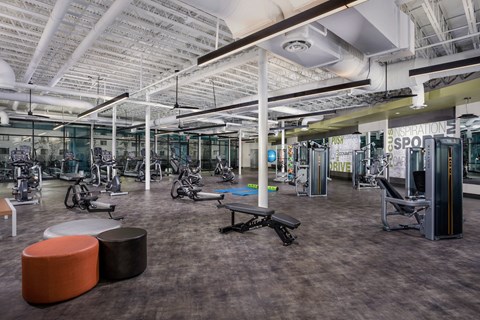a gym with exercise machines and other equipment in a building with cement floors
