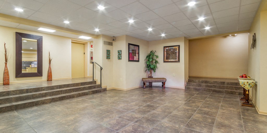 a lobby with a staircase and a plant in the corner