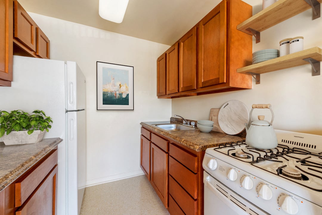 A kitchen with a white stove and wooden cabinets.