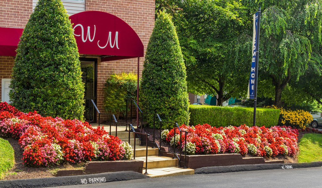 a building with a red awning and a garden of flowers