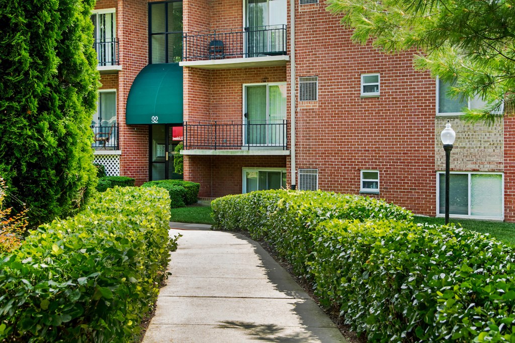 a sidewalk in front of a brick apartment building