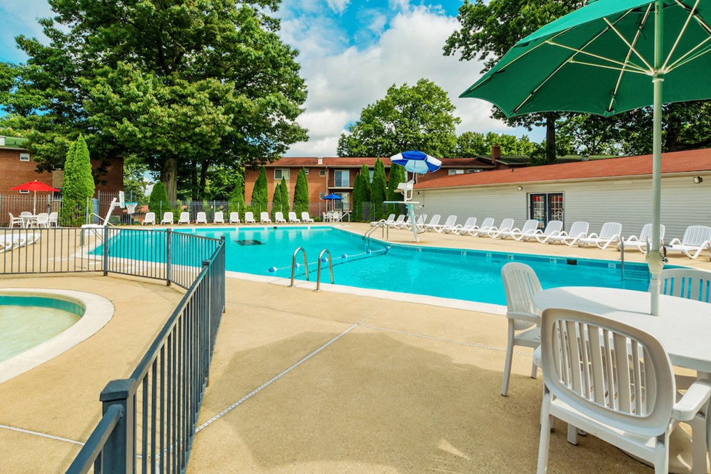 our resort style swimming pool is filled with chairs and umbrellas