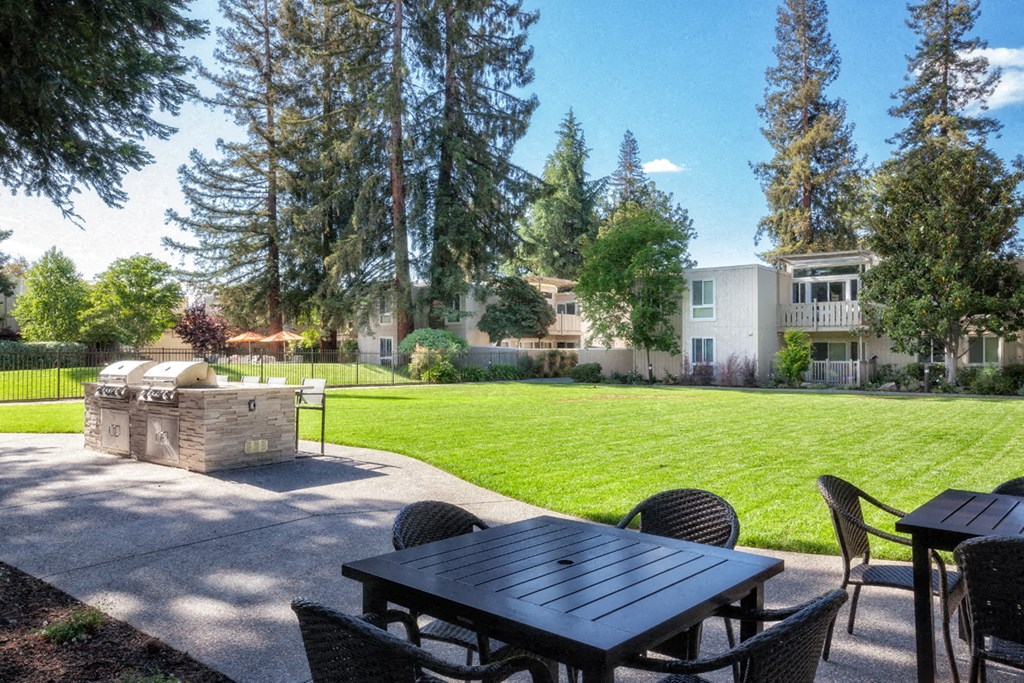 a patio with a table and chairs and a grill