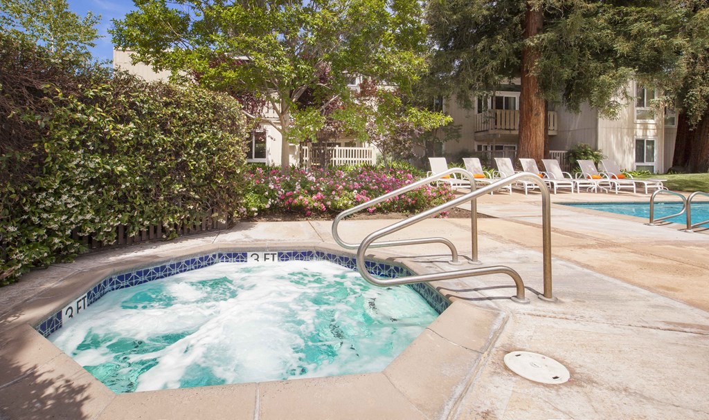 a hot tub in a pool next to a building with chairs