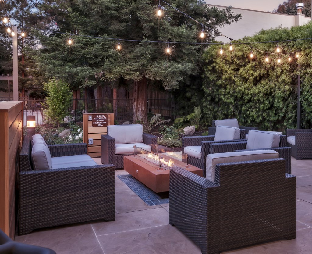 a patio with chairs and a fire pit and lights