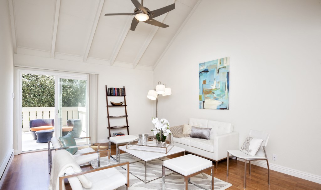a living room with white furniture and a ceiling fan