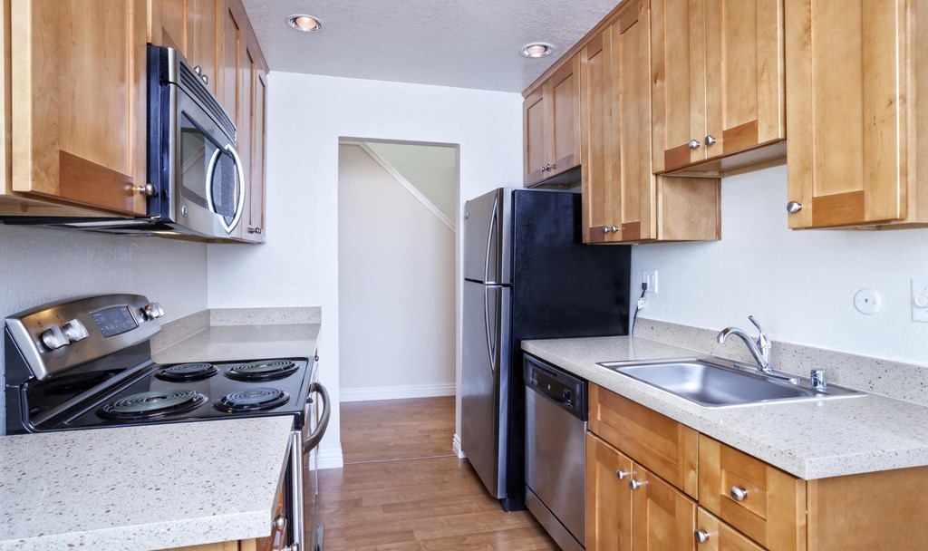 an empty kitchen with wooden cabinets and stainless steel appliances