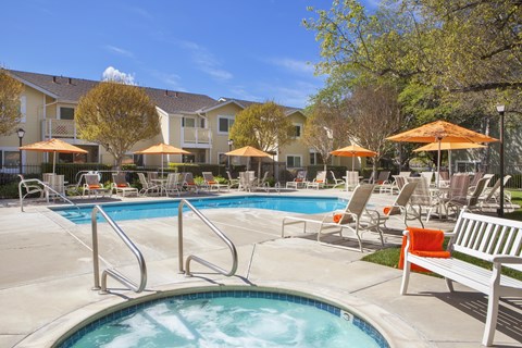 A pool with a hot tub and chairs around it.
