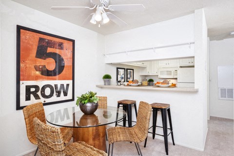 a dining room with a table and chairs and a kitchen in the background