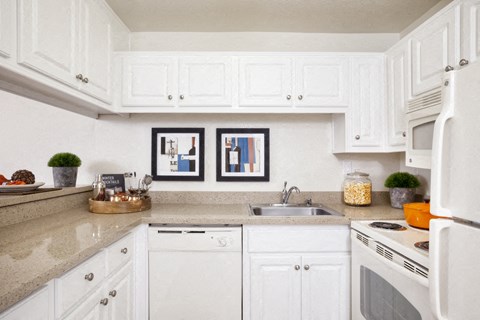 a white kitchen with white cabinets and a sink
