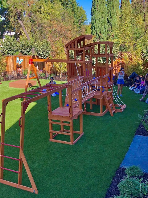 A wooden playground structure with a slide and a ladder.