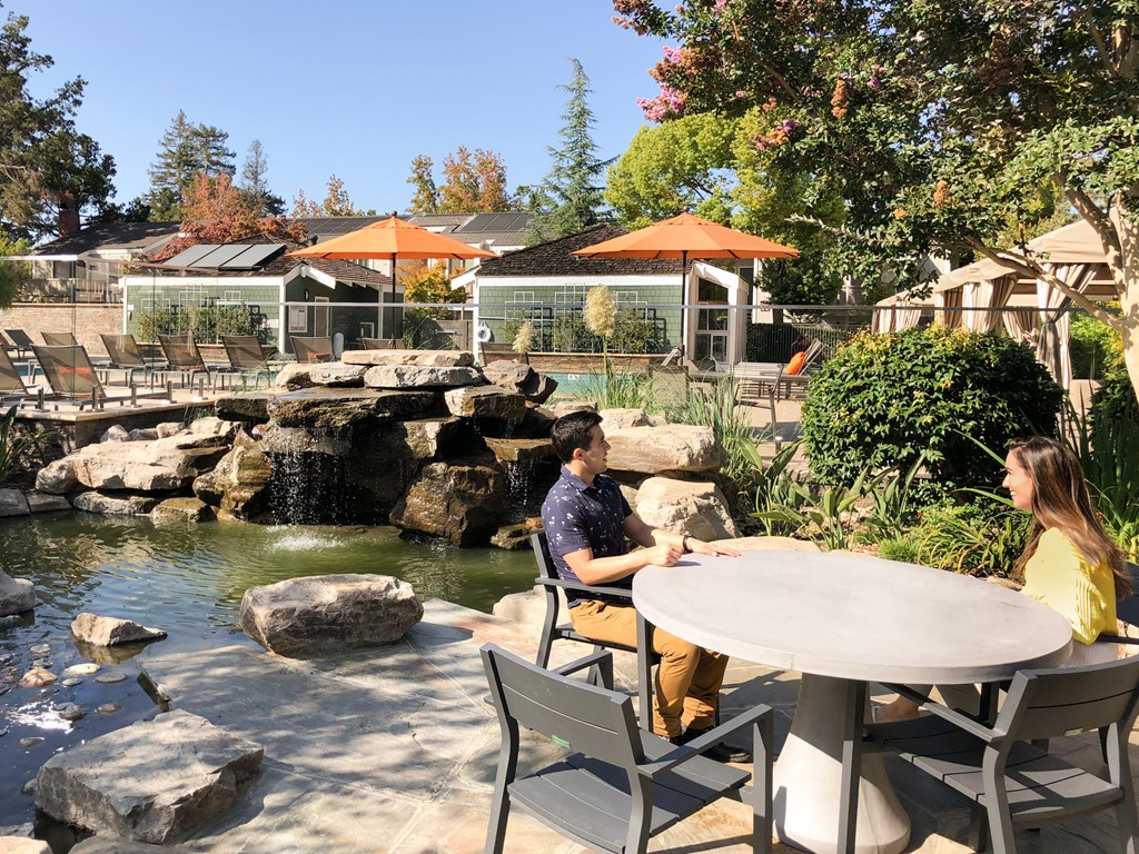 two people sitting at a table in front of a pond