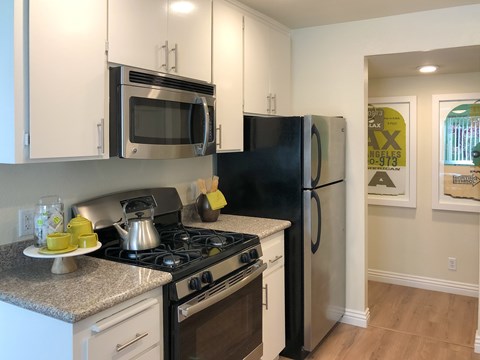 A black refrigerator sits next to a stove in a kitchen.