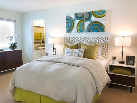 A bedroom with a large bed and a painting on the wall.