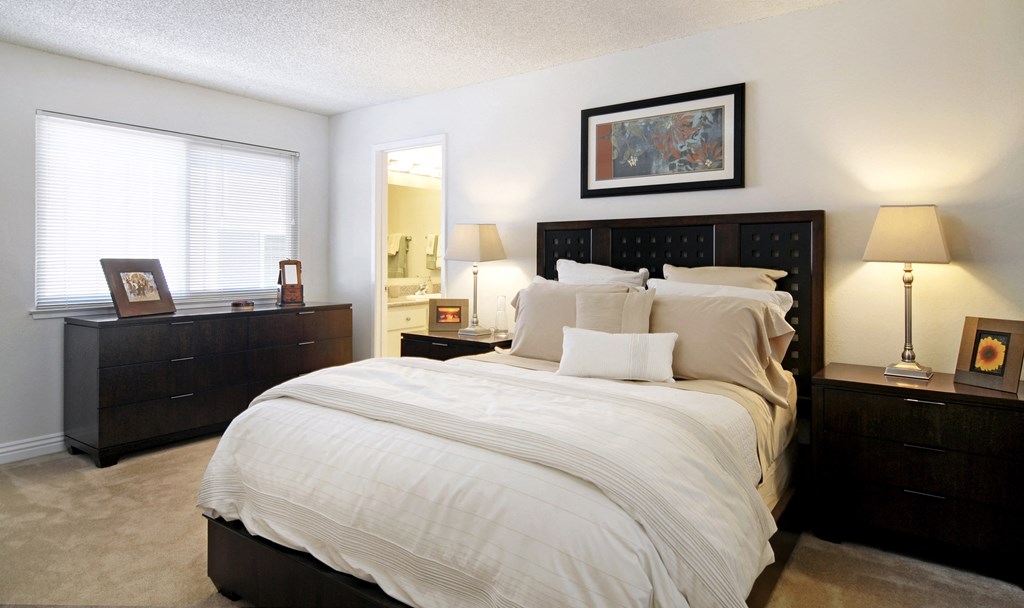 a bedroom with a bed and two dressers and a mirror