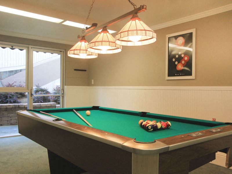 a pool table in a game room with lamps