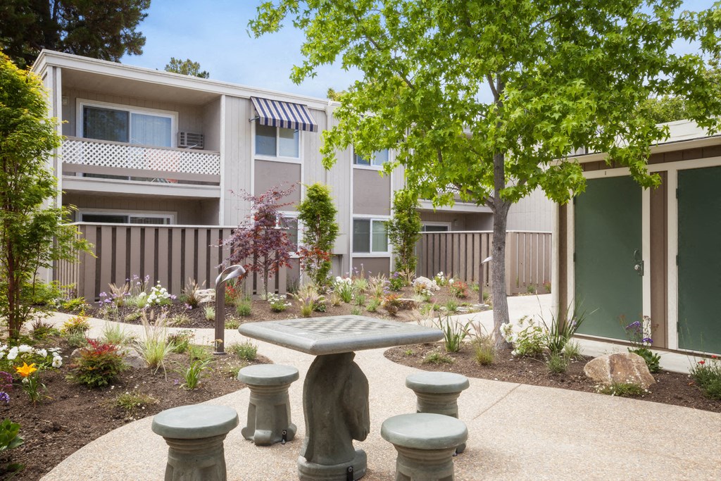 a courtyard with a table and benches in front of an apartment building