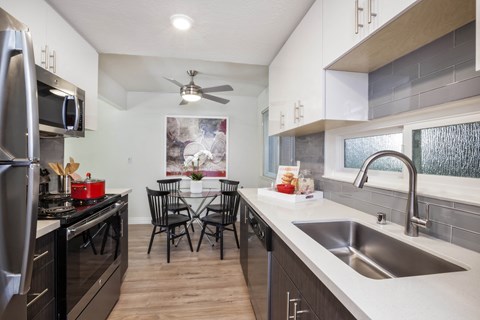 view of kitchen and dining area with stainless steel appliances and counter tops and a sink