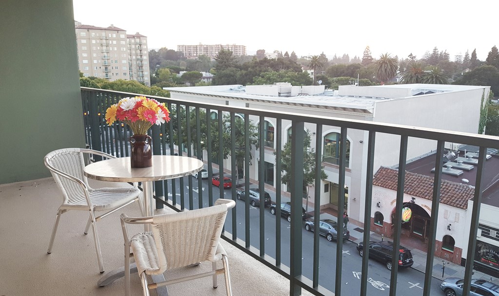 a balcony with a table and chairs and a view of a city