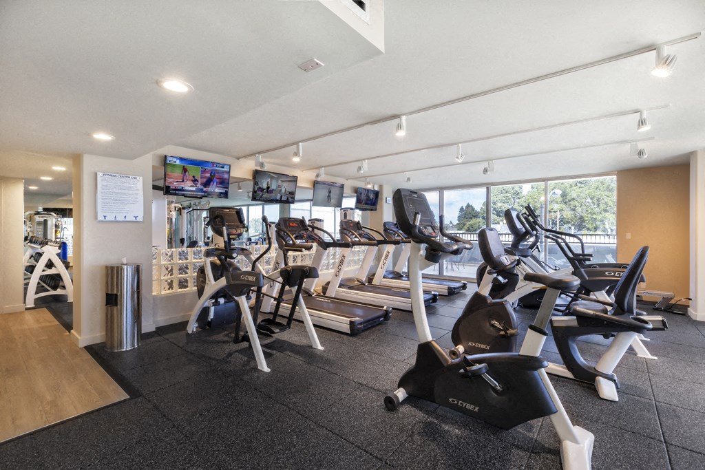a gym with cardio equipment and a large window