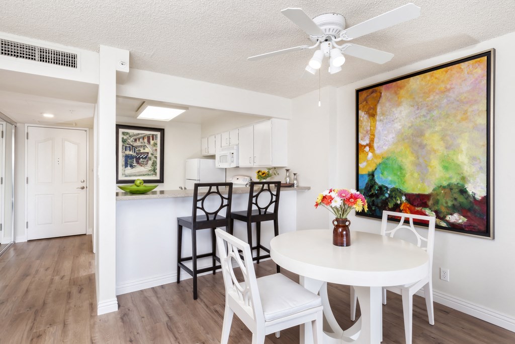 a dining room and kitchen with a table and chairs and a ceiling fan