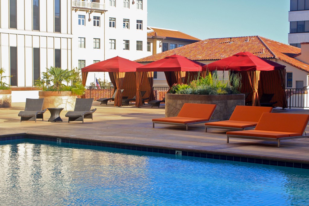 a swimming pool with orange lounge chairs and umbrellas at a hotel