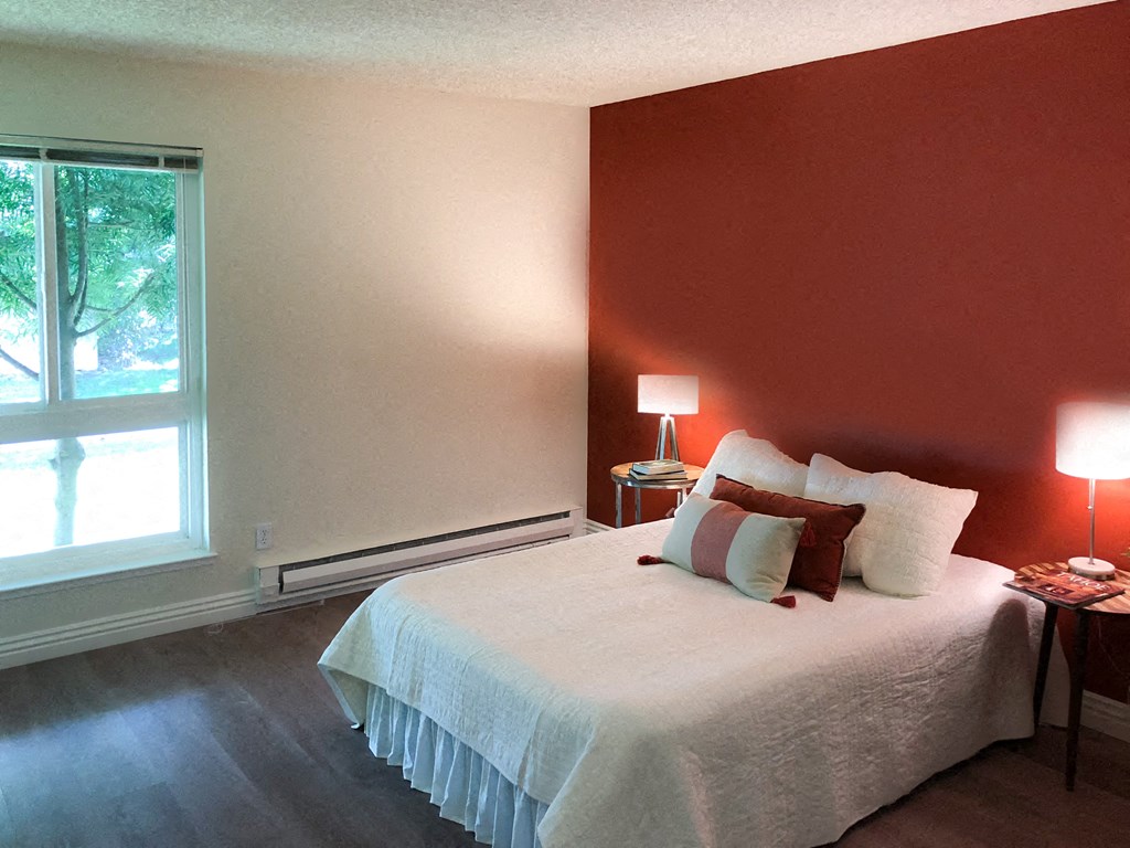 a bedroom with a white bed and a red wall
