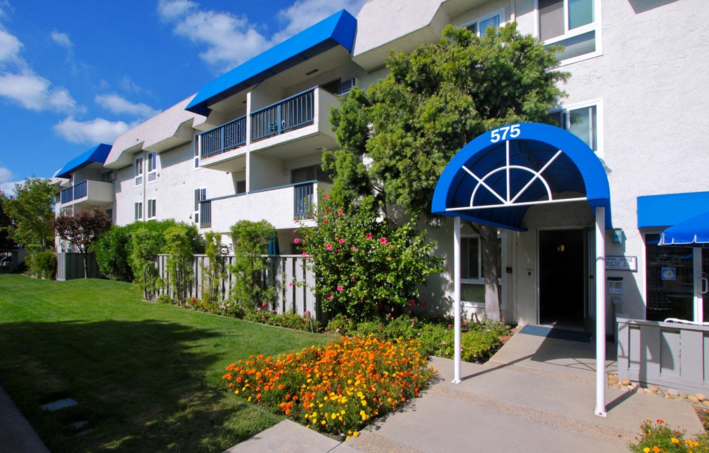 the front of an apartment building with a lawn and flowers