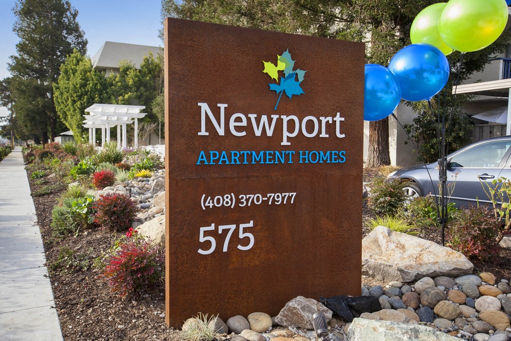 a sign apartment homes in front of a garden with balloons