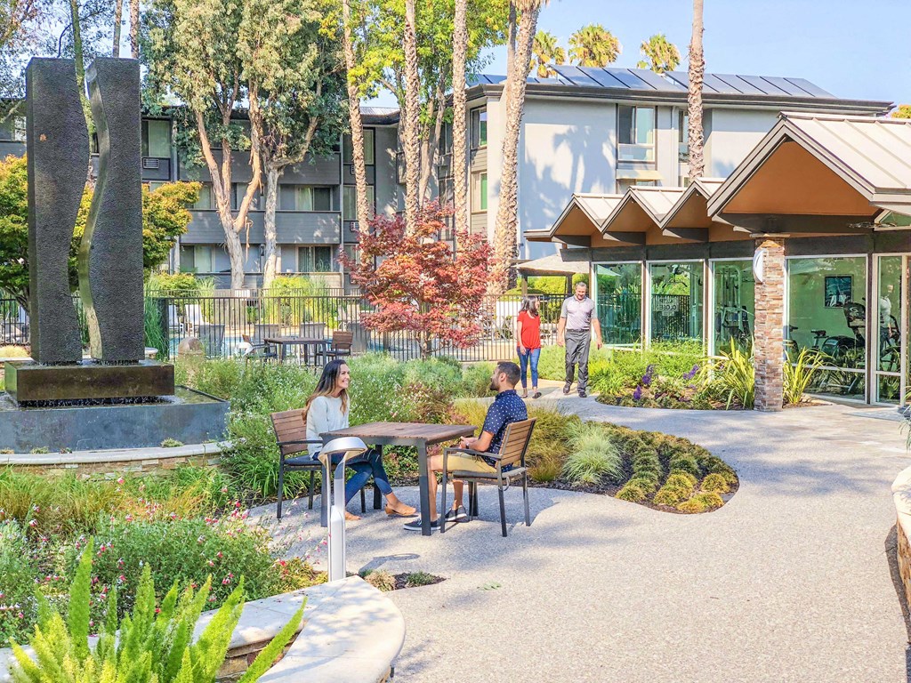 a group of people sitting at a table in a courtyard