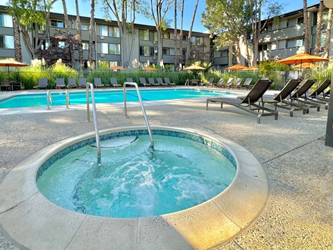 A round hot tub sits in the middle of a pool surrounded by chairs.