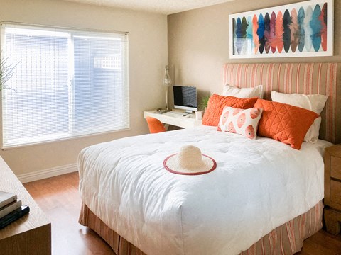 a bedroom with a bed with orange pillows and a hat on it