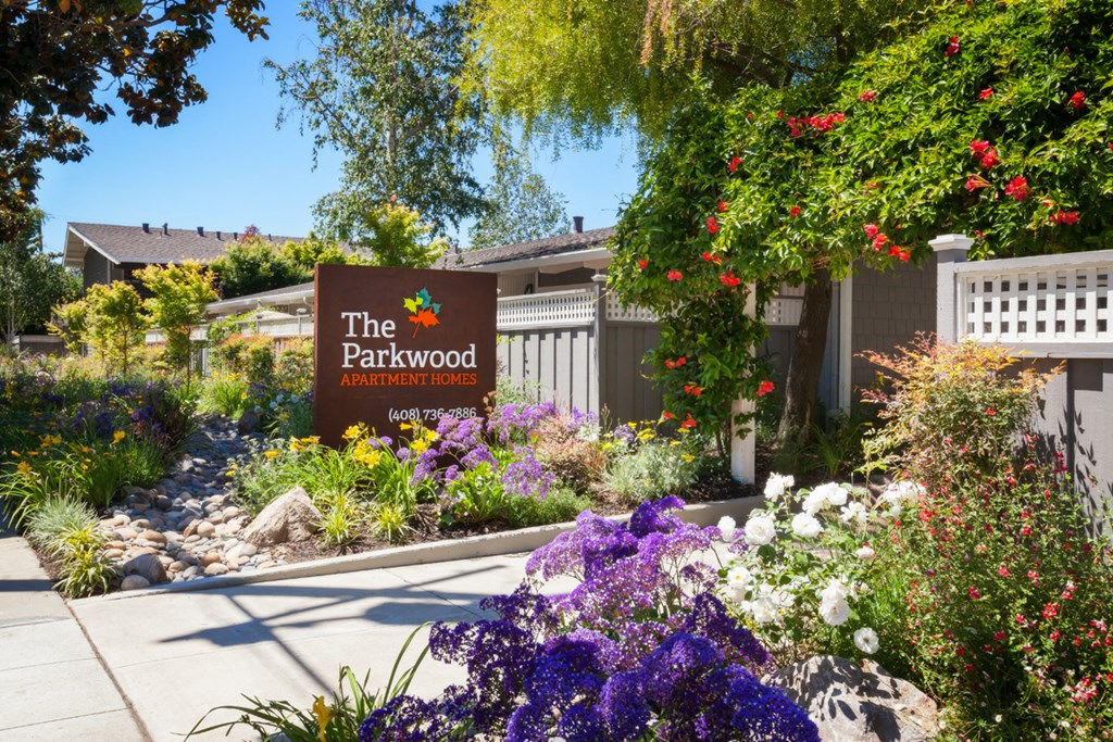 a garden with flowers and a parkwood sign