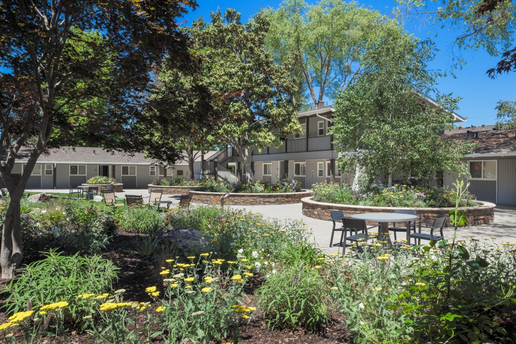 a garden with tables and benches in front of a building