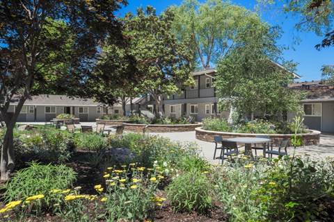 a garden with tables and benches in front of a building