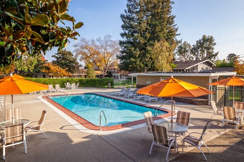 a pool with orange umbrellas and tables and chairs around it