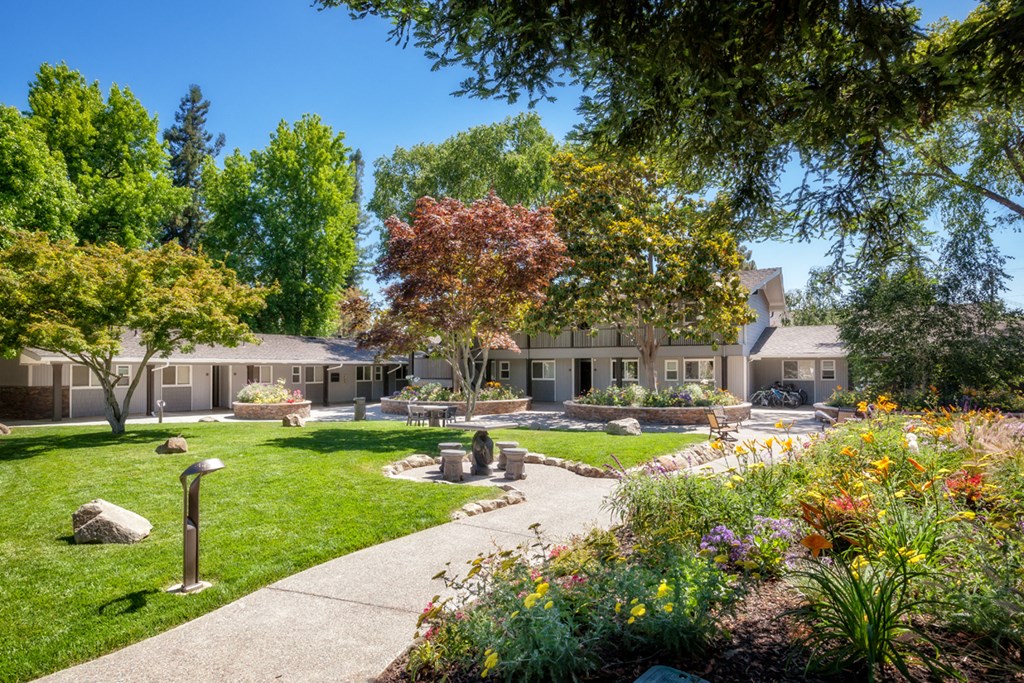 a walkway through a garden in front of a building