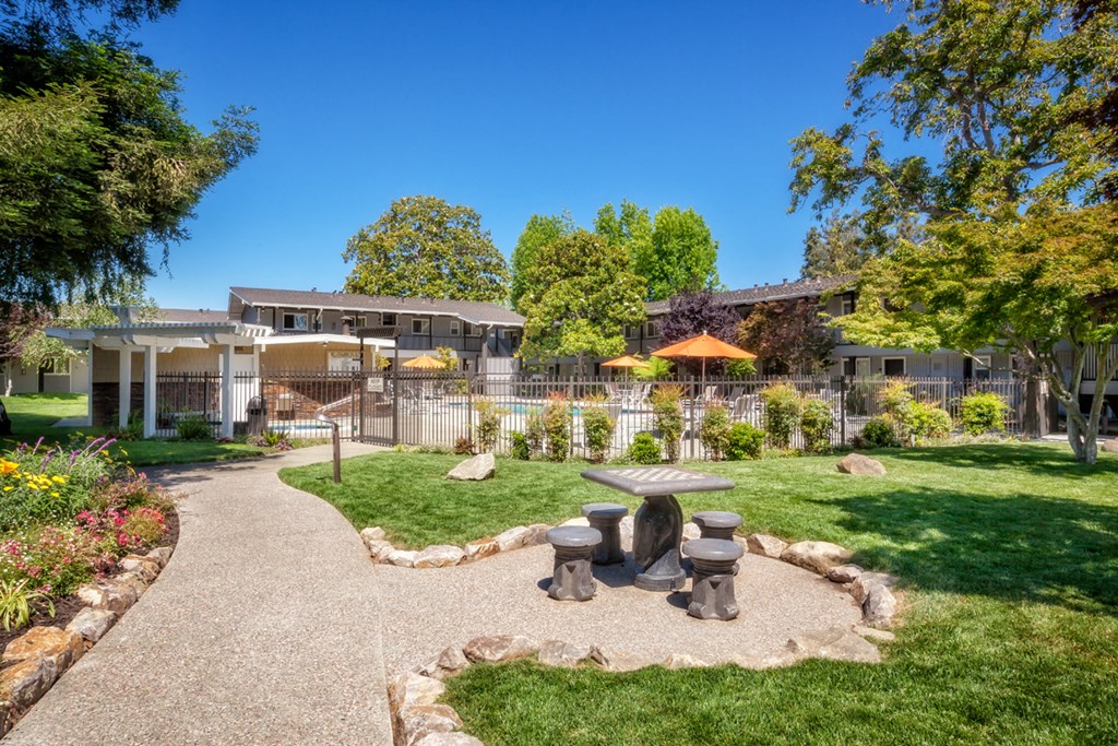 a courtyard with a picnic area and a house in the background