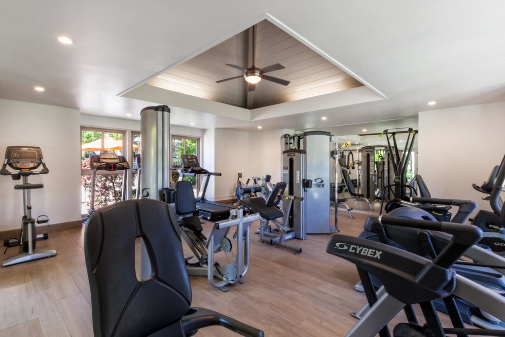 a gym with various exercise machines and a ceiling fan