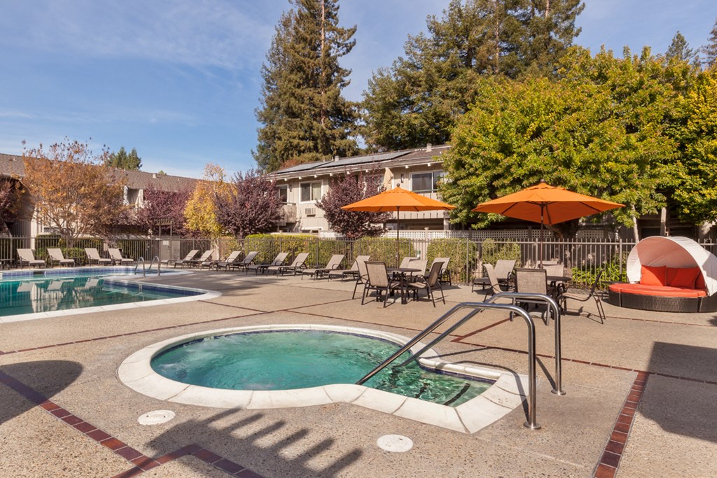 a swimming pool with chairs and umbrellas and a building in the background