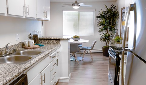 a kitchen with white cabinets and granite counter tops and a table with a chair