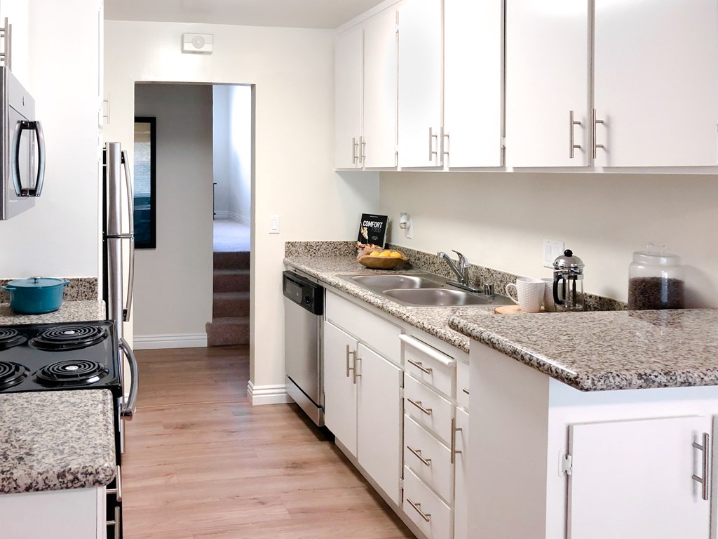 a kitchen with white cabinets and granite counter tops