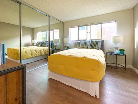 A bedroom with a yellow bed and a mirror on the wall.