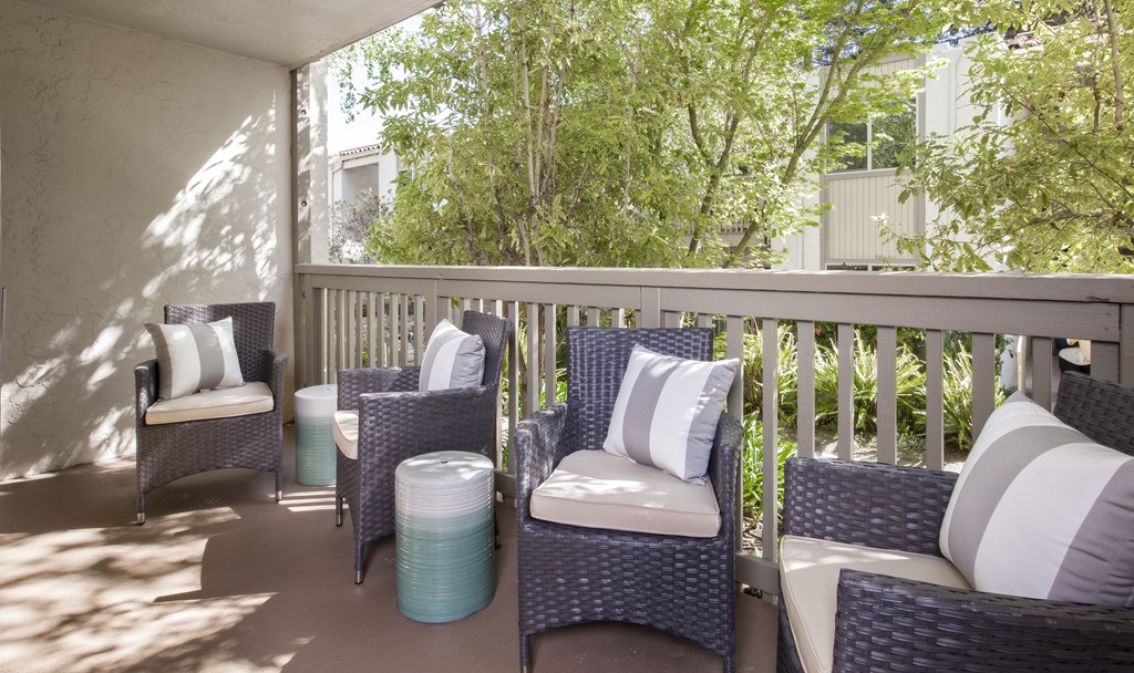 a porch with wicker chairs and a table on a balcony