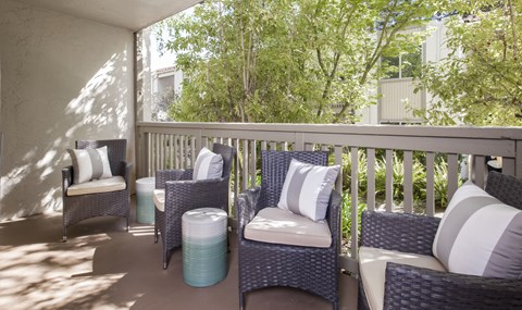a porch with wicker chairs and a table on a balcony