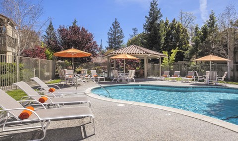 a swimming pool with chairs and umbrellas next to a resort style pool