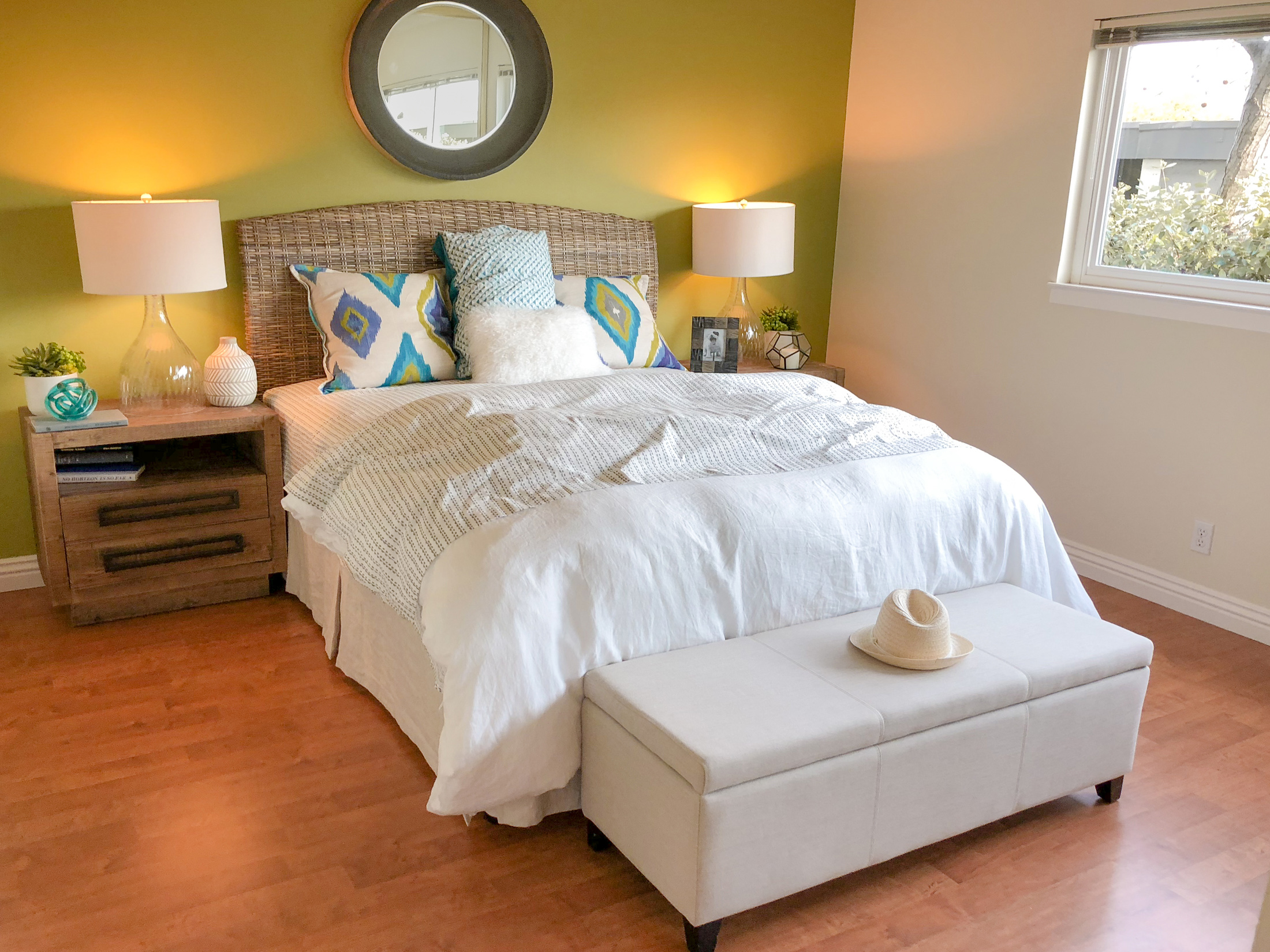 A bedroom with a white bed and a hat on the ottoman.