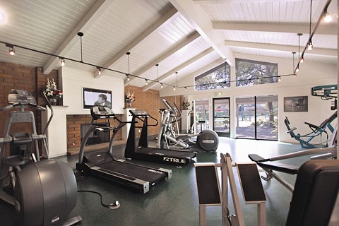 A gym with a rowing machine, treadmill, and exercise bikes.
