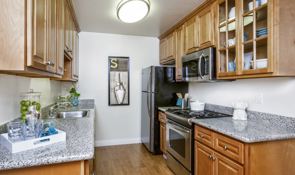 a kitchen with wood cabinets and granite counter tops and a black refrigerator
